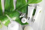 Creams and lotions next to a green leaf.