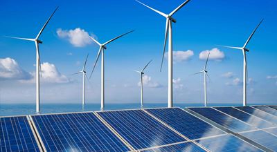Blue sky and sea with solar panels and wind turbines for green energy